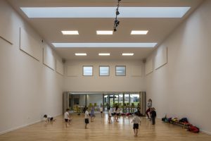 kids exercising interior view - University of Cambridge Primary School by Marks Barfield Architects